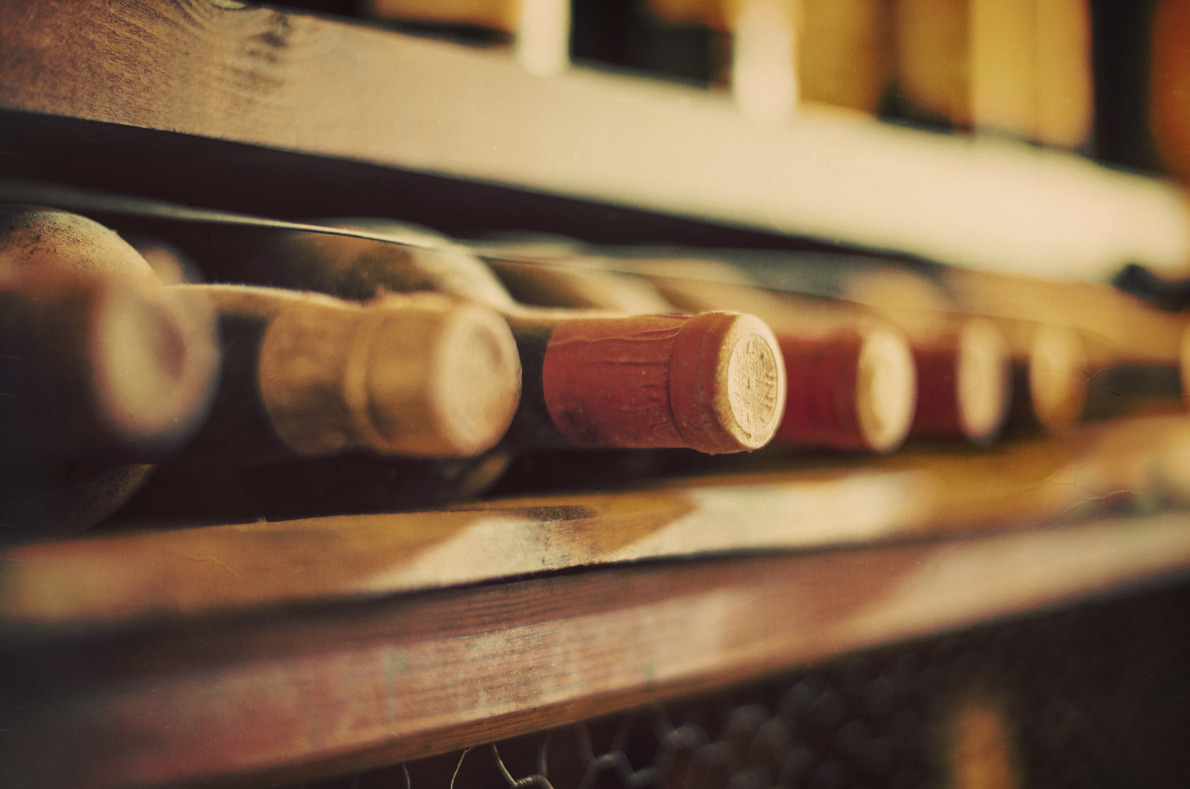 Wine bottles stacked on wooden racks. Vintage effect.